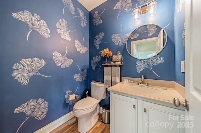 half bath featuring baseboards, wood finished floors, toilet, and vanity