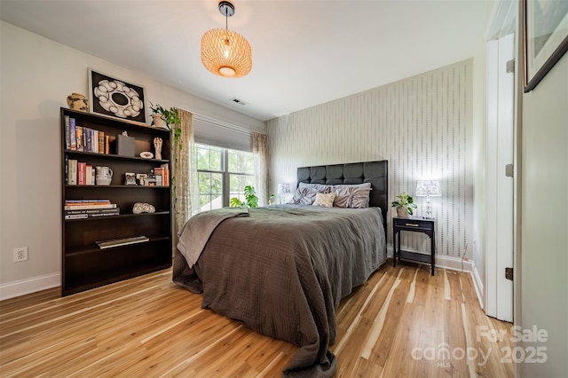 bedroom with visible vents, light wood-style flooring, and baseboards