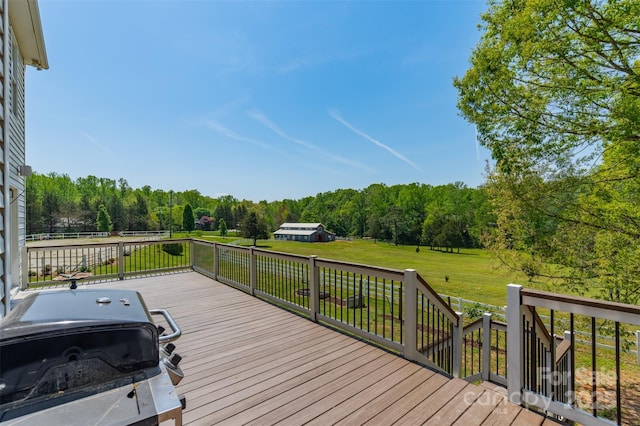 wooden terrace with a yard, a forest view, and a grill