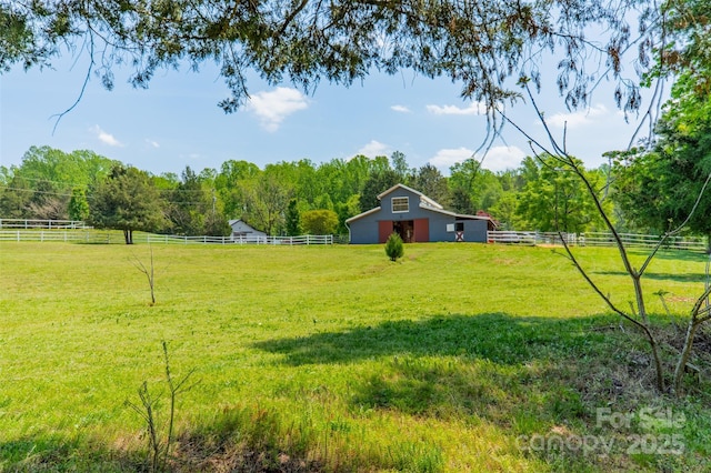 view of yard featuring an outdoor structure, fence, a rural view, and a barn