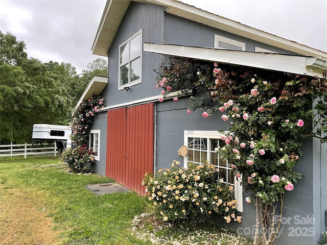 view of side of home featuring fence, concrete block siding, and a yard
