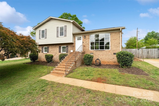 split level home with fence, a front lawn, and brick siding