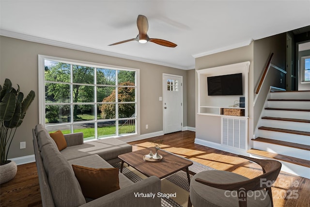 living room featuring crown molding, stairway, baseboards, a ceiling fan, and wood finished floors