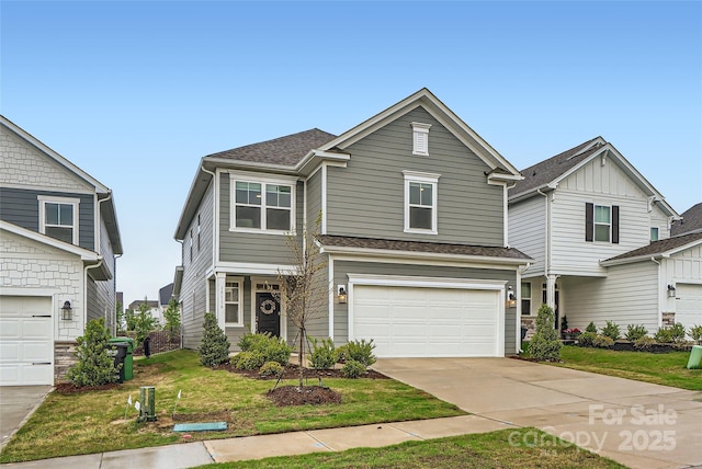 traditional-style house featuring an attached garage, a front lawn, roof with shingles, and driveway