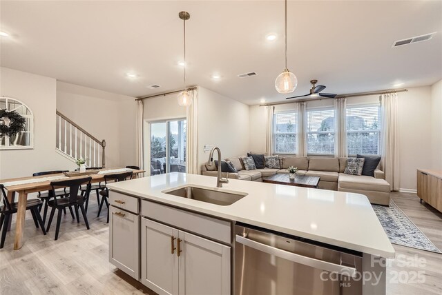 kitchen with a sink, visible vents, light wood finished floors, and dishwasher
