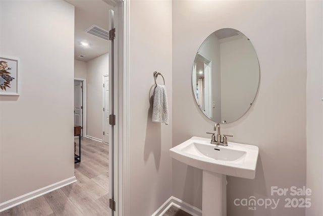 bathroom with baseboards, visible vents, and wood finished floors