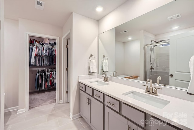 bathroom featuring a sink, a stall shower, double vanity, and visible vents