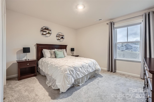 bedroom featuring visible vents, baseboards, and light carpet