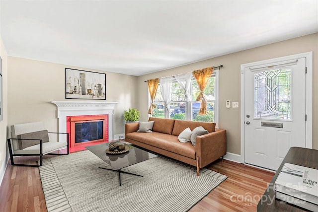 living area with light wood-style floors, a brick fireplace, and baseboards