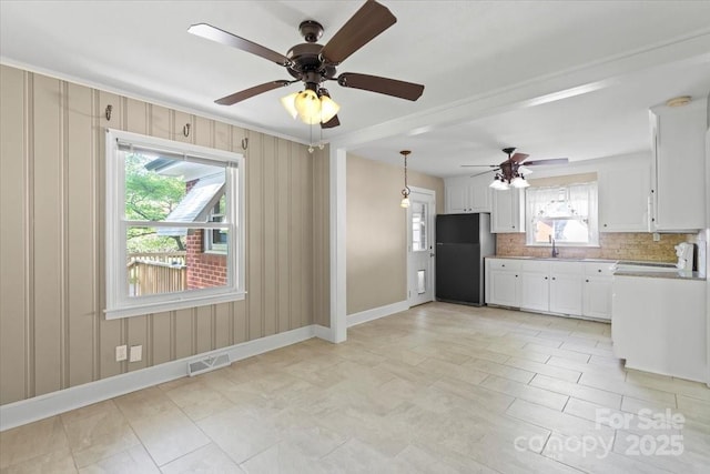 kitchen with a ceiling fan, tasteful backsplash, a sink, visible vents, and freestanding refrigerator