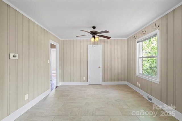 spare room featuring ceiling fan, baseboards, ornamental molding, and stone finish floor