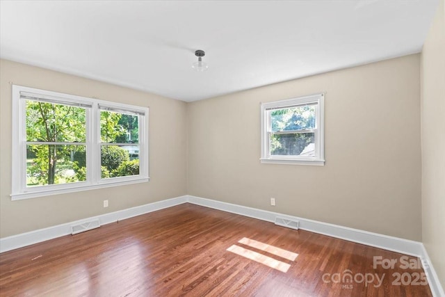 unfurnished room featuring plenty of natural light, visible vents, and baseboards