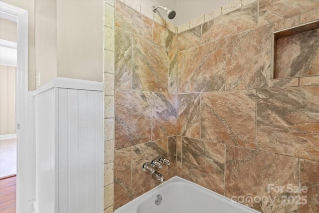 room details featuring wainscoting and shower / bath combination