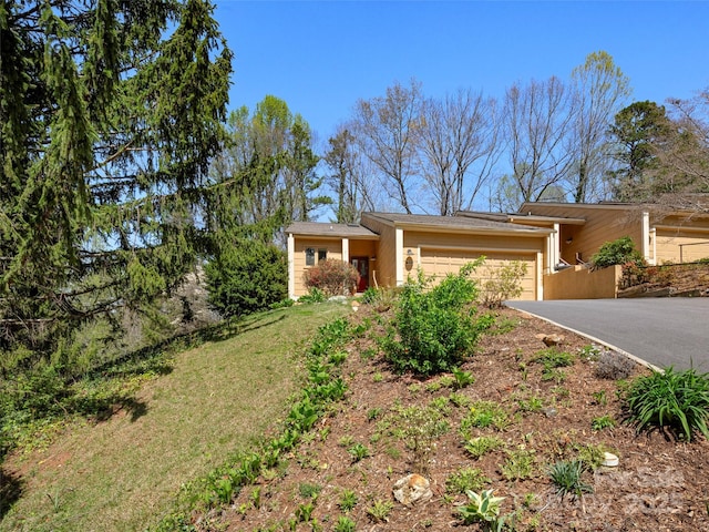 view of front of property with a front yard, driveway, stucco siding, and an attached garage