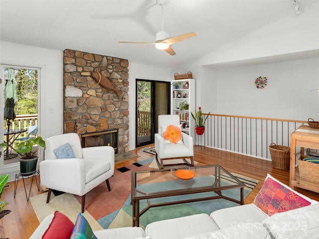 living area with ceiling fan, a stone fireplace, wood finished floors, and a healthy amount of sunlight