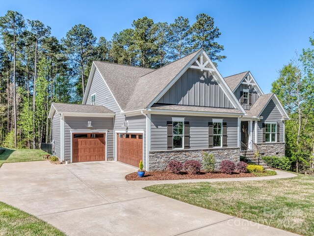 143 Robinson Ridge Dr, Mooresville, NC 28117 - craftsman house with concrete driveway, board and batten siding, stone siding, an attached garage, and a front yard