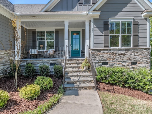 143 Robinson Ridge Dr, Mooresville, NC 28117 - view of exterior entry with board and batten siding, a porch, and stone siding