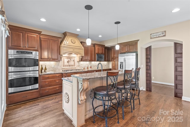 3005 Dream Catcher Cir, Fort Mill, SC 29715 - kitchen with light stone counters, arched walkways, stainless steel appliances, custom range hood, and tasteful backsplash