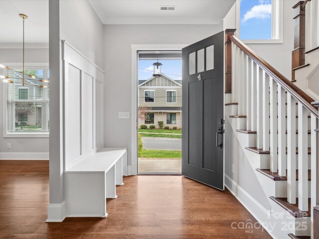entryway featuring visible vents, baseboards, wood finished floors, and stairs