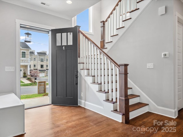 entrance foyer featuring visible vents, baseboards, stairway, and wood finished floors