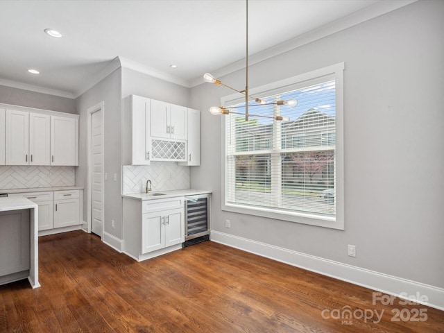 kitchen with tasteful backsplash, ornamental molding, light countertops, and beverage cooler