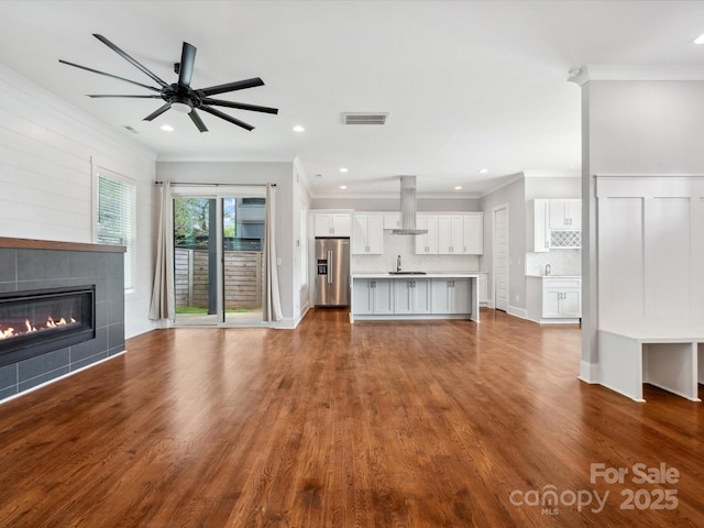unfurnished living room featuring ornamental molding, visible vents, recessed lighting, and a tile fireplace