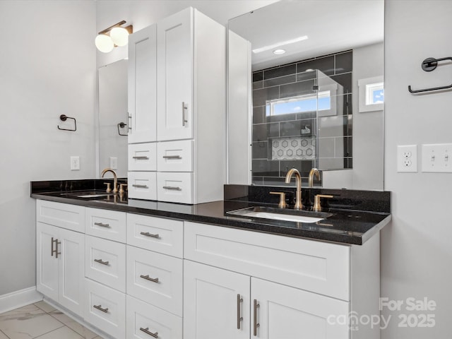 bathroom with tiled shower, double vanity, marble finish floor, and a sink