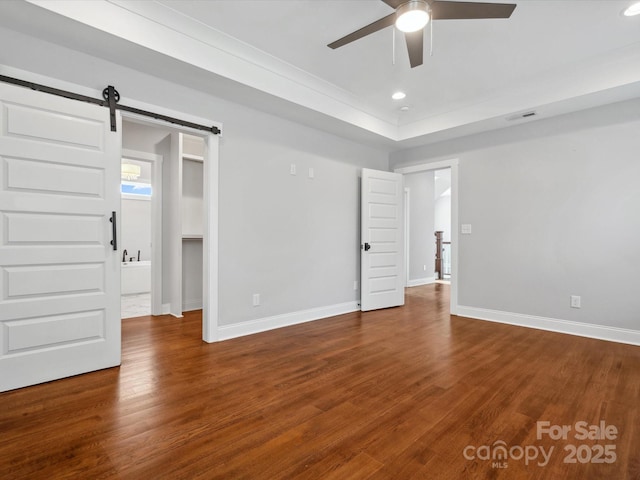 unfurnished bedroom with a barn door, baseboards, and wood finished floors