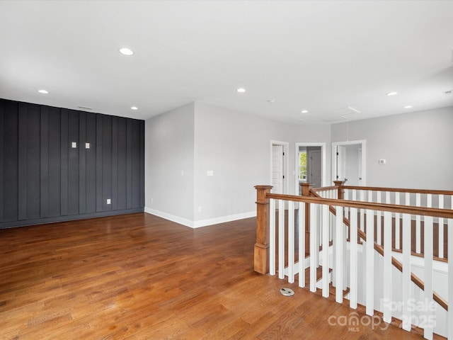 spare room featuring baseboards, recessed lighting, attic access, and wood finished floors