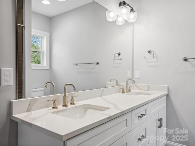 bathroom with toilet, double vanity, and a sink