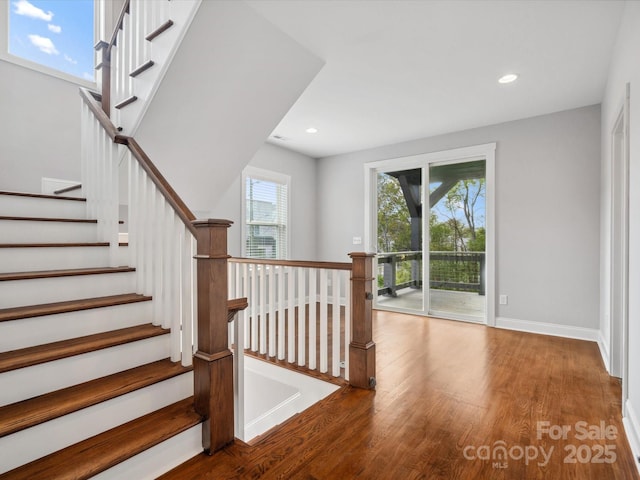 stairway featuring wood finished floors, baseboards, plenty of natural light, and recessed lighting