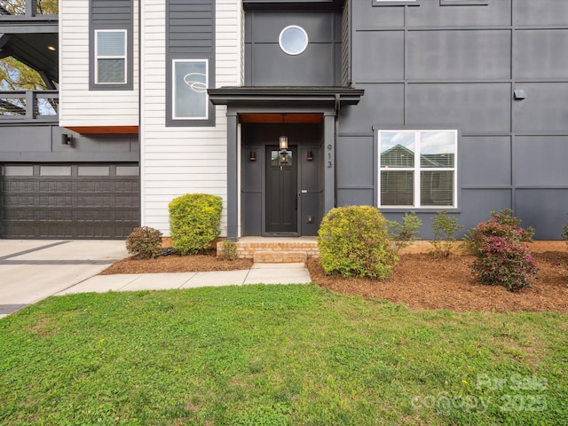 property entrance featuring a garage, concrete driveway, and a lawn