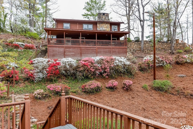exterior space with a chimney, a wooden deck, and stairs