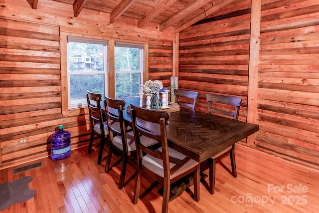 dining area featuring visible vents, wooden ceiling, wood walls, vaulted ceiling with beams, and light wood finished floors