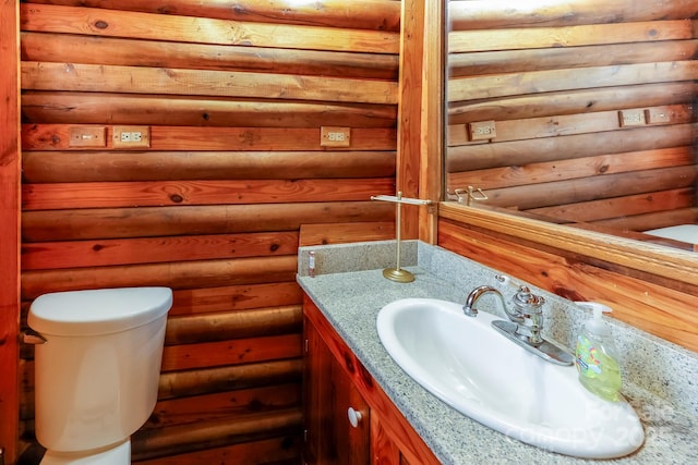bathroom featuring toilet, log walls, and vanity
