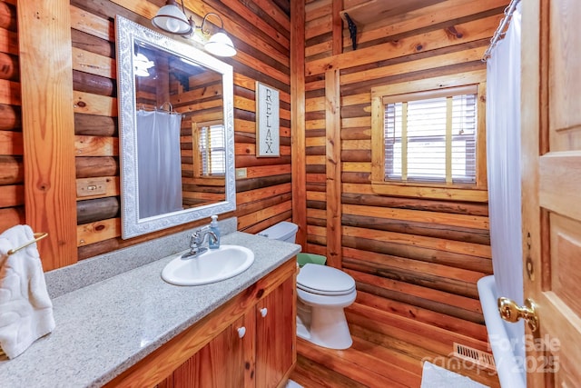 bathroom featuring vanity, a shower with curtain, visible vents, toilet, and log walls