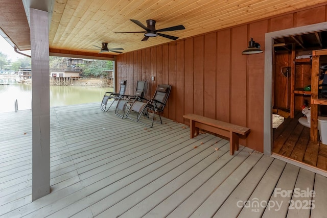 wooden deck with a ceiling fan and a water view