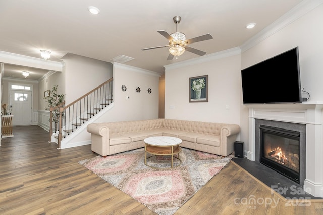 living room featuring crown molding, a ceiling fan, wood finished floors, and stairs