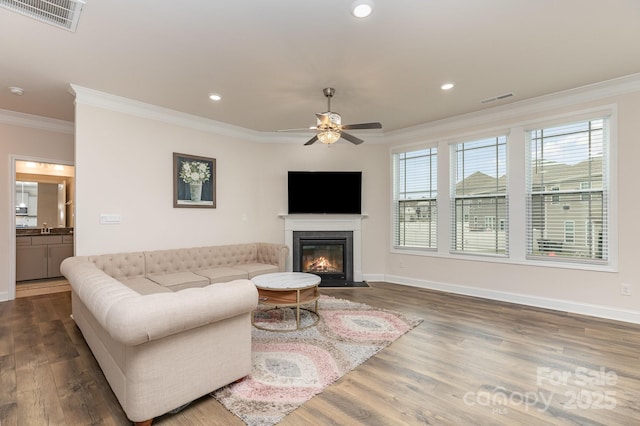 living area with ceiling fan, ornamental molding, and visible vents