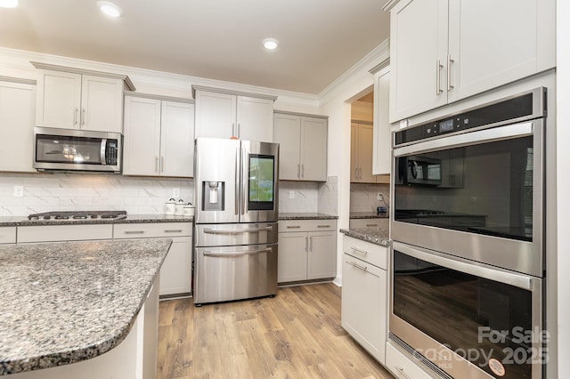 kitchen featuring light wood-style floors, crown molding, stone countertops, stainless steel appliances, and backsplash