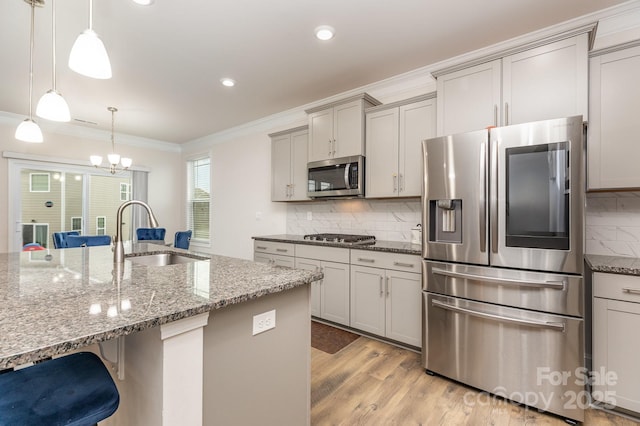 kitchen featuring a sink, crown molding, stainless steel appliances, gray cabinets, and a breakfast bar area