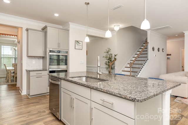 kitchen with crown molding, light wood-style floors, visible vents, stainless steel appliances, and a sink