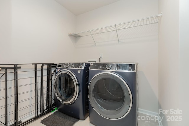 clothes washing area featuring laundry area, baseboards, and washing machine and dryer