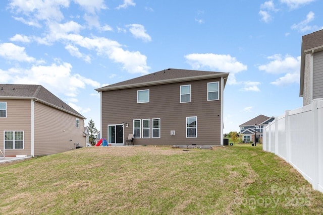 rear view of property featuring fence and a lawn