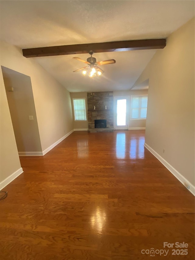 unfurnished living room featuring plenty of natural light, baseboards, and vaulted ceiling with beams
