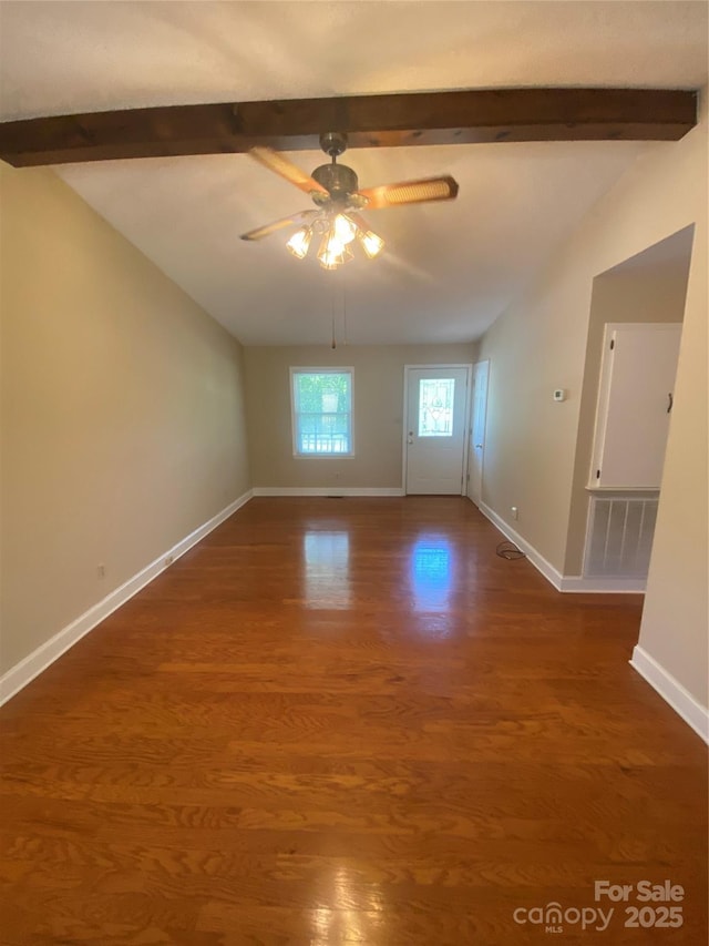spare room featuring ceiling fan, visible vents, wood finished floors, vaulted ceiling with beams, and baseboards
