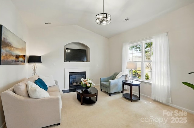 carpeted living room featuring baseboards, a glass covered fireplace, vaulted ceiling, and visible vents