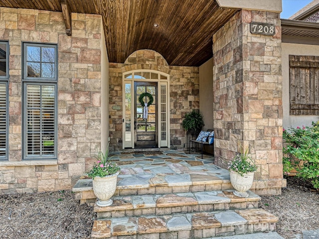 property entrance featuring stone siding and covered porch