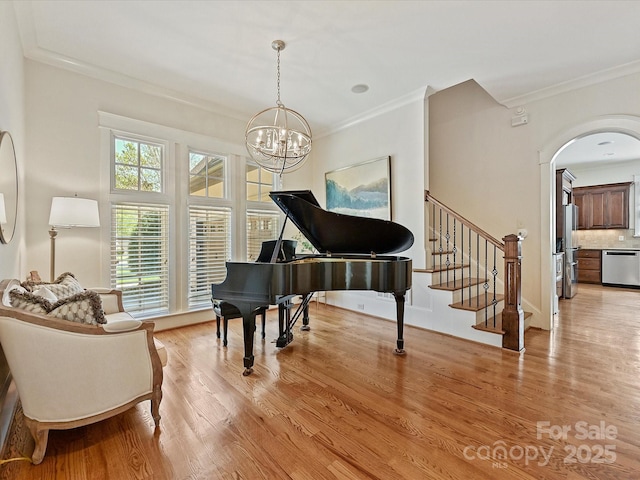 sitting room featuring ornamental molding, light wood-type flooring, stairway, a chandelier, and arched walkways