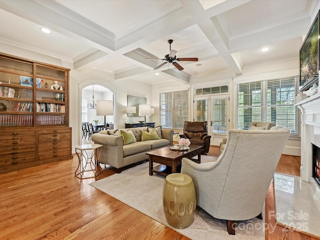 living room featuring light wood-style floors, beamed ceiling, and a premium fireplace